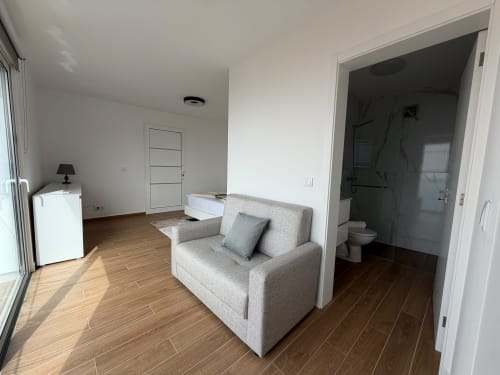 Estúdio moderno na villa Sunshine 85 House em Ribeira Brava com poltrona bege, kitchenette, banheiro e piso em madeira