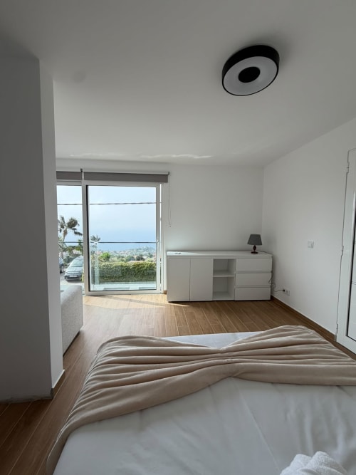 Quarto espaçoso com vista para o mar na villa Sunshine 85 House na Madeira, piso em madeira, mobiliário moderno e vistas oceânicas