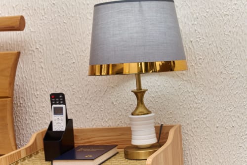 Lampe de bureau moderne à abat-jour gris et finitions dorées à l'Hôtel Yakro, Yamoussoukro, près d'une télécommande et d'un carnet