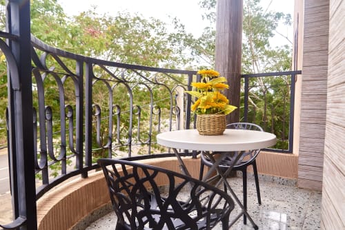 Balcon de l'Hôtel Yakro à Yamoussoukro avec table ronde blanche, chaises noires, fleurs jaunes et vue sur la forêt