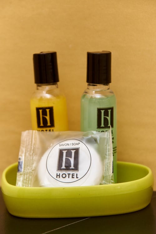 Ensemble d'articles de toilette de l'Hôtel Yakro à Yamoussoukro dans un plateau vert clair : shampooing jaune, après-shampooing vert et savon