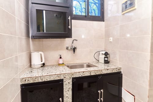Salle de bains moderne de l'Hôtel Yakro Yamoussoukro avec plan de travail en granit, meuble-lavabo noir et vasque murale