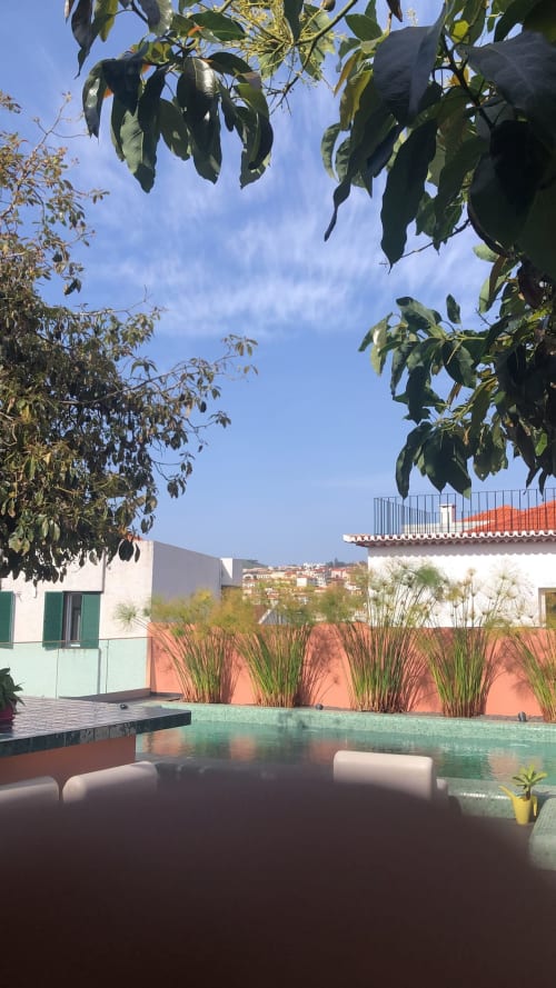 Terraço da Villas Simone com piscina turquesa, espreguiçadeiras, paredes de coral e vegetação exuberante com vista para a encosta portuguesa