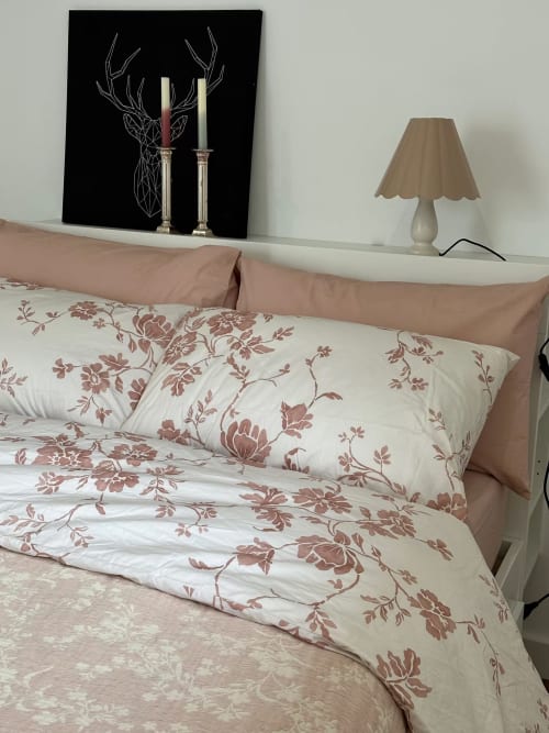 Quarto das Villas Simone com roupa de cama floral, obra de arte com veados, castiçais e luminária de mesa