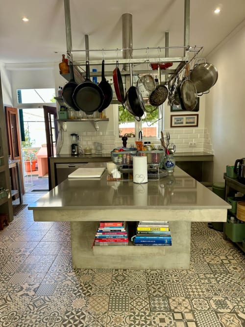 Cozinha moderna em Villas Simone com ilha em aço inoxidável, panelas suspensas, azulejo metrô branco e piso estampado
