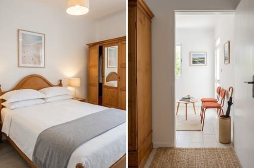 Suite de quarto Villas Simone com móveis em madeira, roupa de cama branca e área de estar adjacente com poltronas