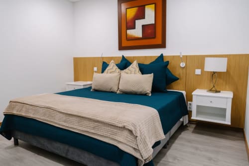 Quarto moderno da Villa Amore com roupa de cama verde-azulado, cabeceira de madeira e criado-mudo branco em Paul do Mar, Portugal