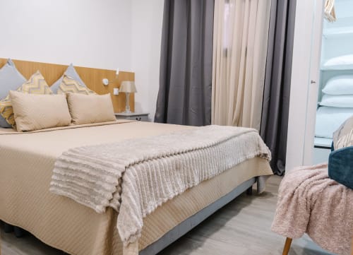 Quarto luminoso na Villa Amore em Paul do Mar, Portugal, com cama de casal, roupa de cama bege e elementos de madeira