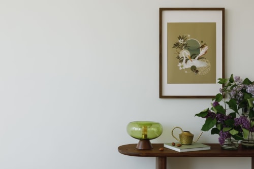 Decoração elegante de quarto nas Villas Simone com obras de arte botânica emoldurada, luminária de vidro verde e flores roxas frescas sobre madeira
