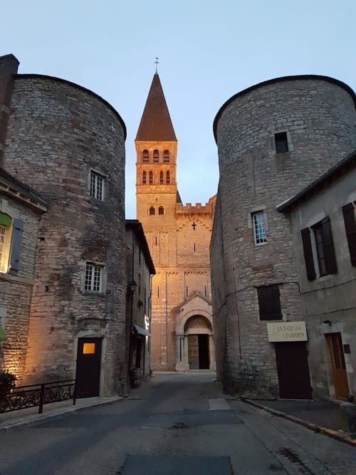 Portail médiéval en pierre à Cluny avec clocher d'église, entrée des Gîtes les Orchidées