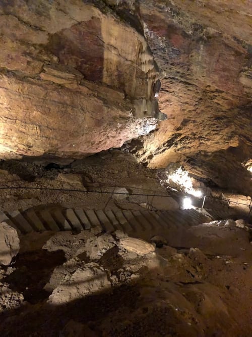 Passage souterrain avec escalier en pierre et parois rocheuses sculptées aux Gîtes les Orchidées, Cluny