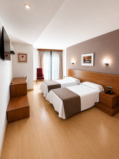 Habitación Deluxe con camas gemelas en Hotel Villa de Cacabelos, con muebles de madera y equipamiento moderno