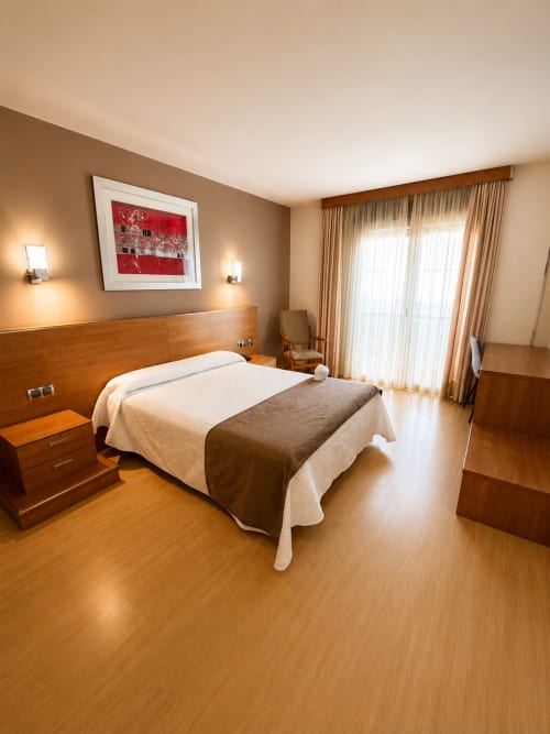 Espacioso dormitorio doble en Hotel Villa de Cacabelos con muebles de madera, iluminación cálida y comodidades modernas en Cacabelos