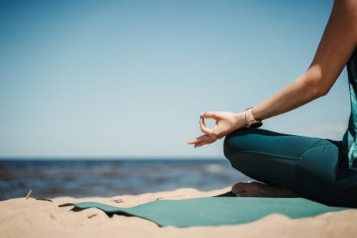 Pessoa em meditação postura de ioga na praia perto da Villa Amore em Portugal com céu limpo e vista para o oceano