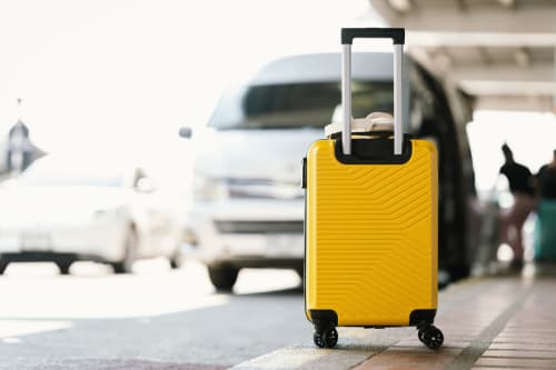 Mala amarela na entrada da Villa Amore Accommodation com carros estacionados ao fundo, Portugal