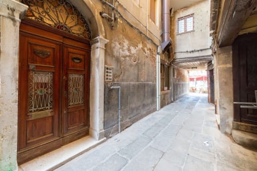 Passaggio veneziano storico con porta in legno ornato e muri in pietra invecchiata vicino a Luxury Loft Venice, Rialto