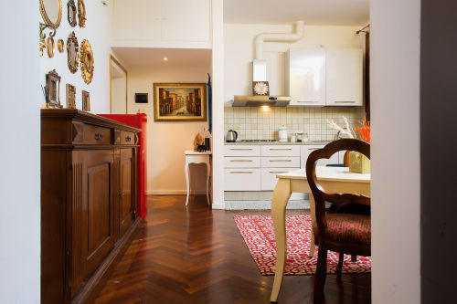 Lussuoso loft veneziano con cucina moderna, mobili in legno scuro, accenti rossi e arredi d'epoca affacciati sul Canal Grande