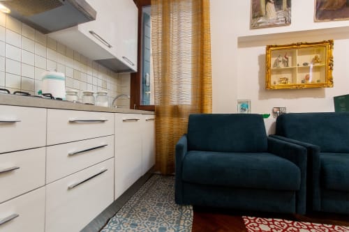 Moderno appartamento a Venezia con cucina bianca, divano blu scuro, specchio dorato e tappeti decorativi Royal