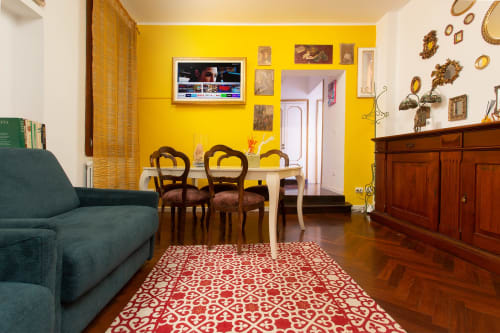 Lussuoso loft veneziano con pareti giallo vivace, tavolo da pranzo, divano verde e specchi ornamentali su parete color crema