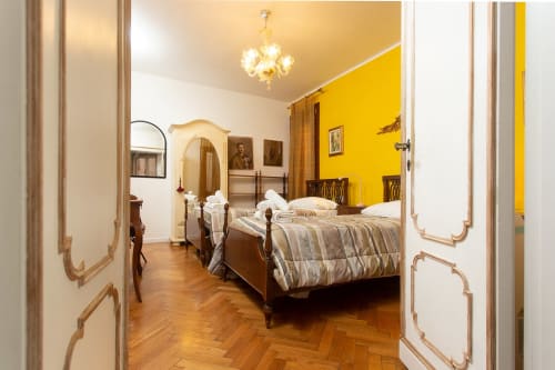 Lussuosa camera da letto a Venezia con letti gemelli, parete gialla, pavimenti in legno e arredi classici al Luxury Loft Venice