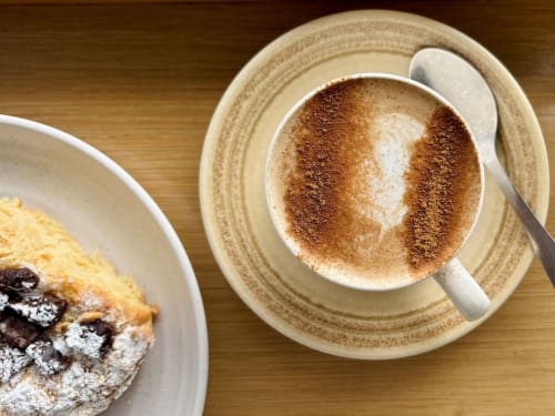 Cappuccino con cacao e pasticceria al servizio colazione di Holiday Suites Pesaro, Italia