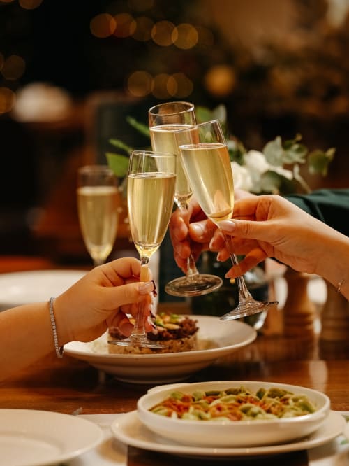 Ospiti che brindano con champagne presso Holiday Suites Pesaro, con piatti gourmet e tavolo festivo