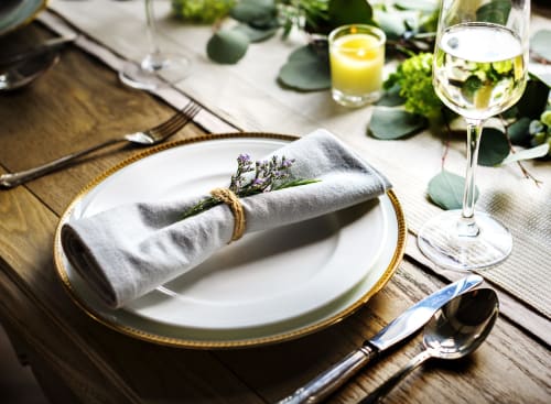 Elegante mise en place presso Holiday Suites Pesaro con tovagliolo arrotolato, calice di vino e centrotavola floreale