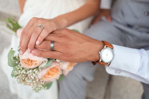 Sposi che mostrano gli anelli nuziali e il bouquet presso Holiday Suites Pesaro