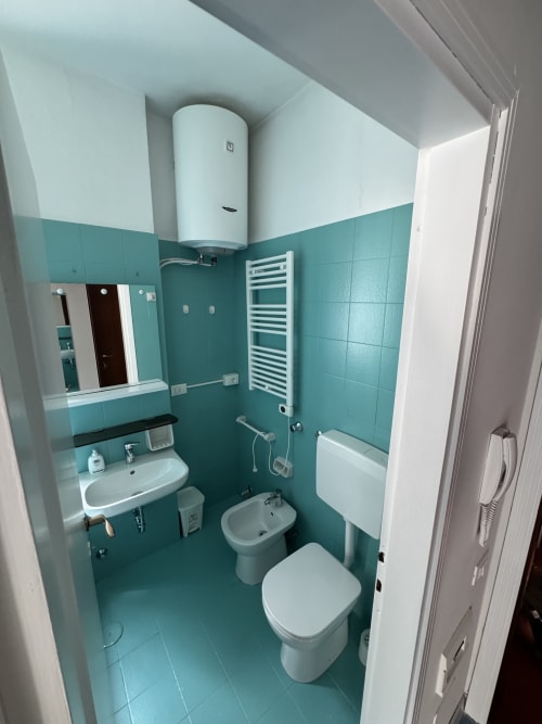 Bagno turquoise moderno presso Porta Romana Suite Milano con lavandino, wc, bidet, porta asciugamani bianco e scaldabagno elettrico