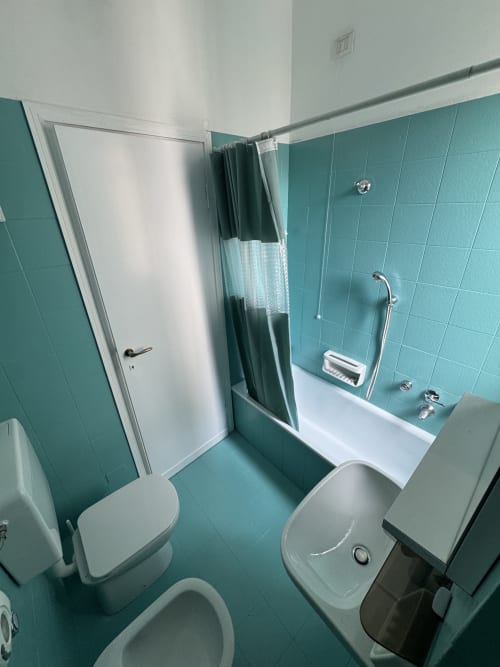 Bagno con piastrelle turchesi, WC, bidet, lavabo e doccia nella Suite Porta Romana di Milano