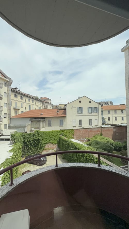 Vista dal balcone della Suite Porta Romana Milano con cortile, muri ricoperti di edera, auto parcheggiata e edifici residenziali