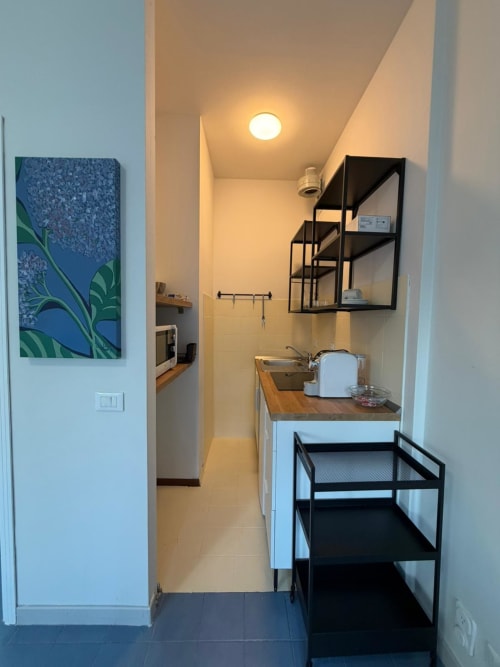 Kitchenette moderna e luminosa nella suite Porta Romana Milano con scaffali neri, lavello e piano di lavoro in legno