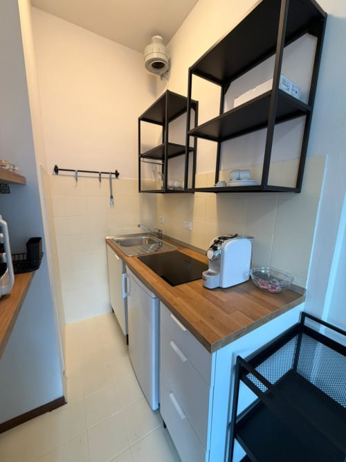 Moderna cucina al Porta Romana Suite Milano con bancone in legno, lavello in acciaio inox e parete nera