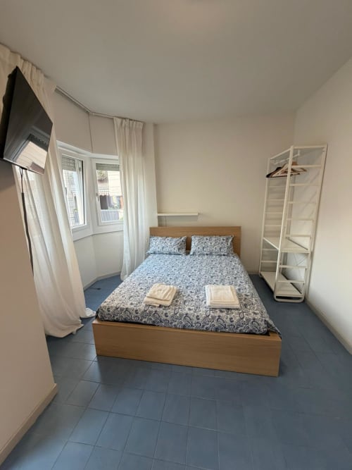 Camera da letto moderna nella Porta Romana Suite Milano con letto in legno, biancheria blu a motivi e arredi contemporanei