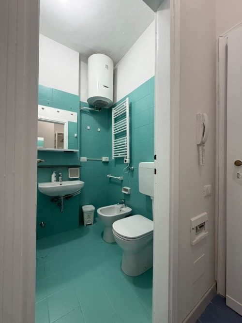 Bagno moderno di Porta Romana Suite Milano con piastrelle turchesi, wc, lavabo, scaldasalviette e scaldabagno