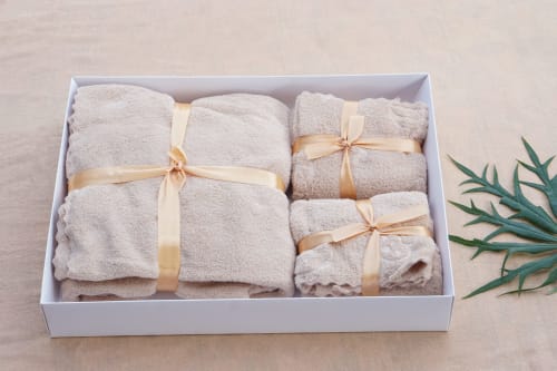 Luxury beige towels with gold ribbons in white box at Holiday Suites, Pesaro