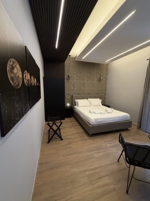 Camera moderna di Eterna Suites Roma con letto queen, arte murale a tema lunare, pavimenti in legno e illuminazione contemporanea