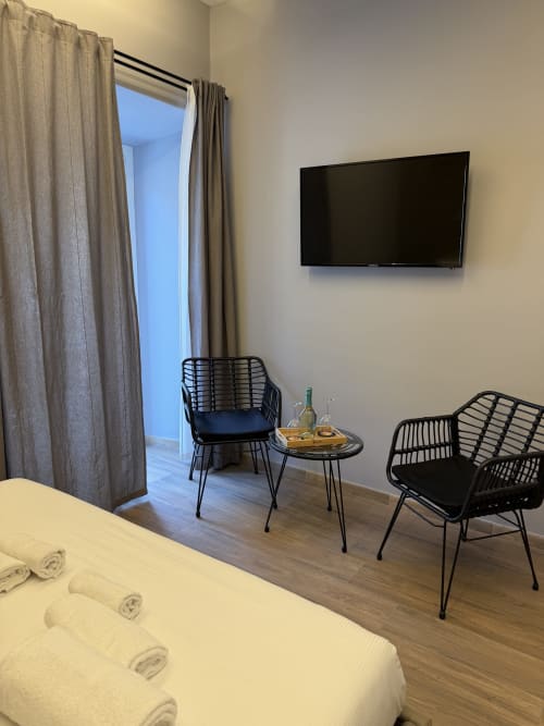Suite moderna presso Eterna Suites Roma con TV a parete, sedie in vimini nero e pavimentazione in legno