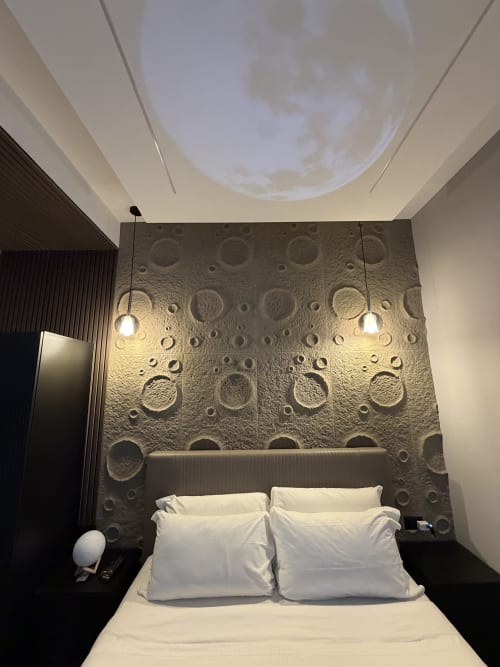 Camera moderna di Eterna Suites Roma con parete decorativa a motivi lunari testurizzati, luci a sospensione e biancheria bianca