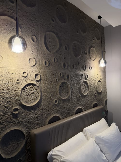 Camera Moon Suite presso Eterna Suites Roma con parete a cratere lunare, luci a sospensione e cuscini bianchi su testata imbottita