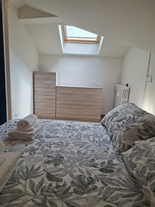 Camera da letto luminosa in mansarda a Le Arche Verona con lucernario, due letti con biancheria decorata, comò in legno e muri bianchi
