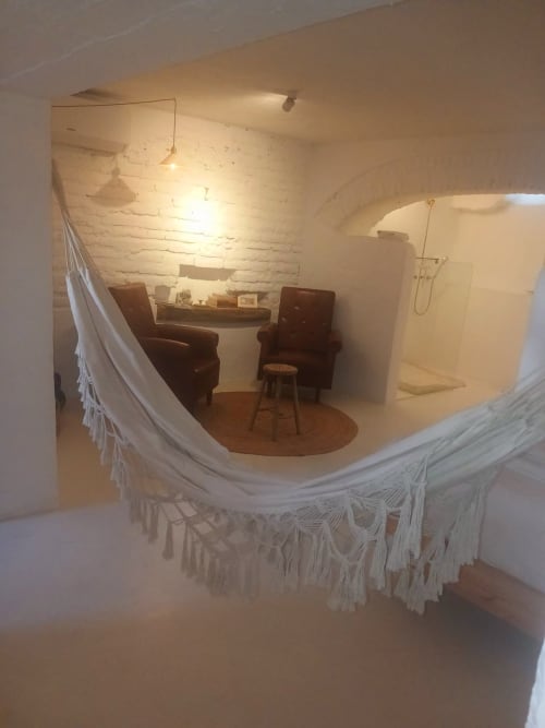 Aconchegante sala de estar no apartamento Casas Velhinhas em Estremoz com poltronas bordeaux, lareira e rede branca