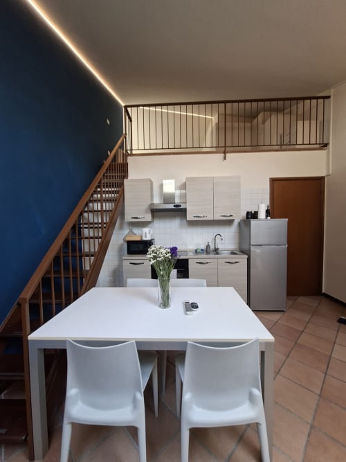 Cucina e zona pranzo moderna a Le Arche Verona con tavolo bianco e elettrodomestici in acciaio inox