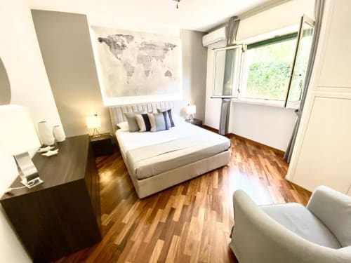 Camera da letto moderna e raffinata presso Mottola Apartments a Tropea con letto matrimoniale, pavimenti in legno, finestre con vista sul giardino e