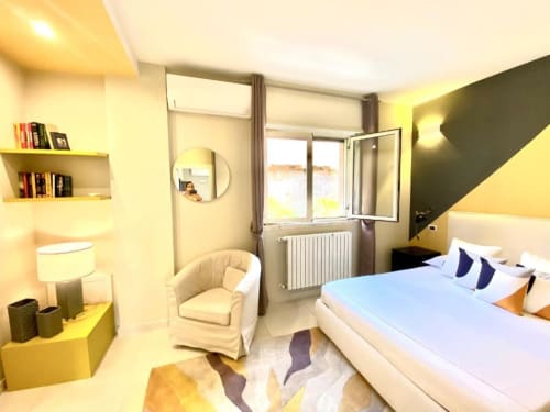 Monolocale moderno alle Mottola Apartments di Tropea con letto, poltrona, librerie e vista giardino dal balcone