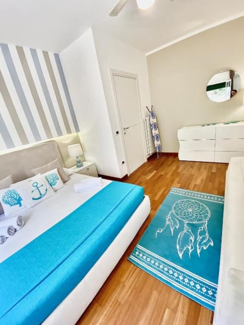 Camera da letto deluxe a Mottola Apartments a Tropea con accenti turchesi, pavimenti in legno e vista giardino
