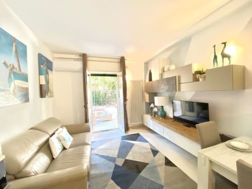 Soggiorno Deluxe presso Mottola Apartments a Tropea con divano, TV, angolo cottura e terrazza con vista sul giardino