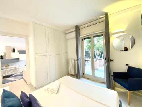 Camera moderna negli Apartamenti Mottala, Tropea, con armadio bianco, porte-finestre affacciate sul giardino e design contemporaneo