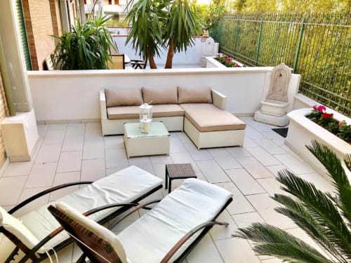 Terrazza degli Appartamenti Mottola a Tropea con lettini, zona salotto e vista giardino circondata dal verde