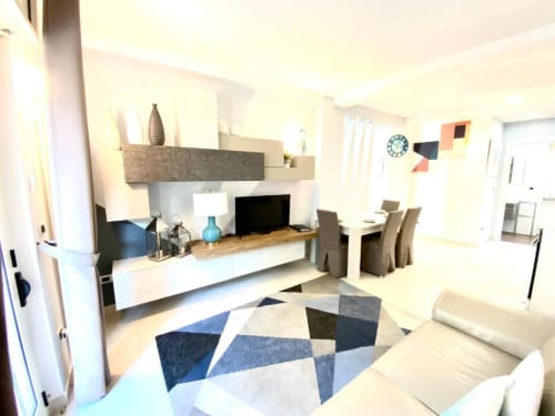 Elegante zona living delle Mottola Apartments Deluxe a Tropea con tavolo da pranzo, mobile TV e tappeto con motivi geometrici